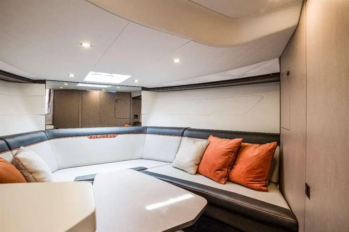 Luxurious interior of a yacht lounge, featuring a grey and black curved seating area with orange cushions and a table.